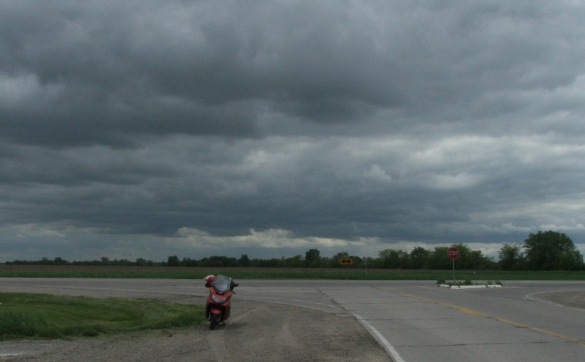 Motor scooter at crossroads under storm clouds.
