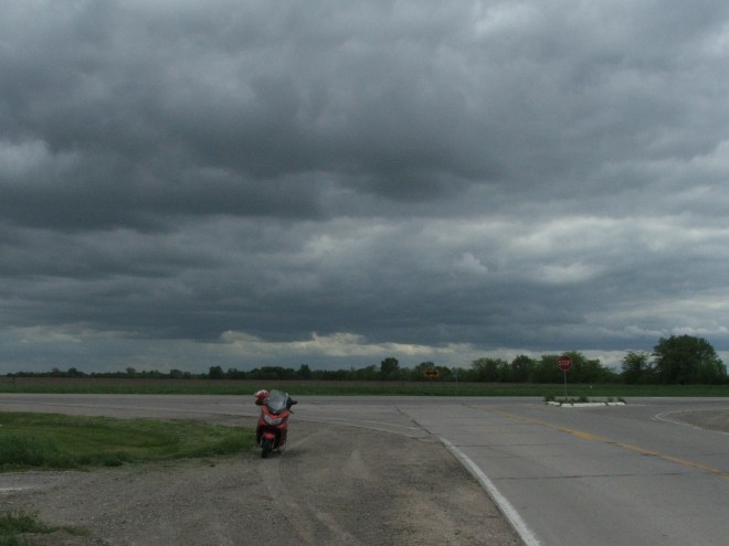 Motor scooter at crossroads under storm clouds.