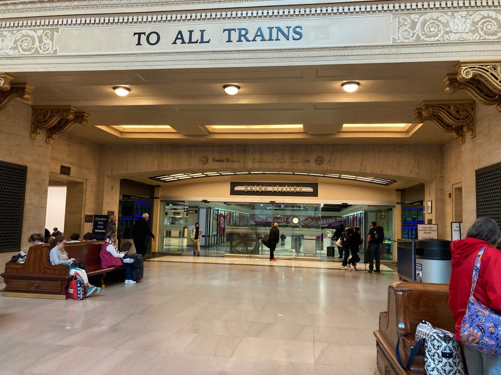 Passengers on benches in station concourse.