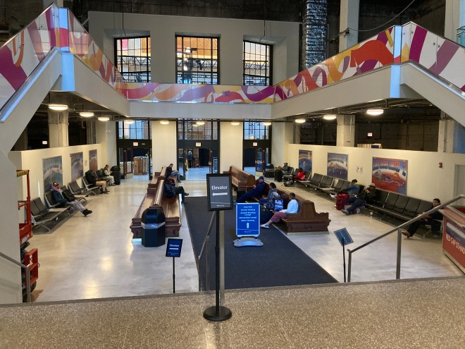 Passengers wait on benches in train station.