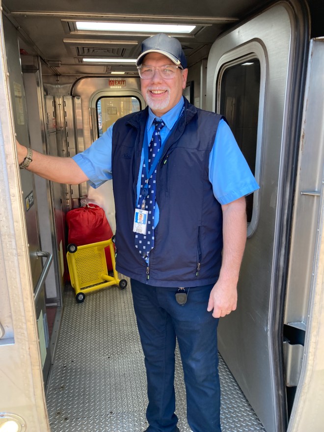 Train crew welcomes passengers to sleeper car.